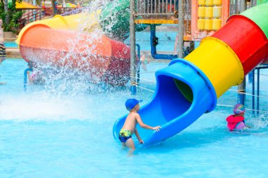 PATTAYA, THAILAND - 10 Mart 2024: Su kaydırağında oynayan küçük çocuk sıcak bir yaz günü Pattaya Park Sahili Tatil Köyü 'nde su birikintisi üzerinde.
