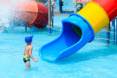 PATTAYA, THAILAND - 10 Mart 2024: Su kaydırağında oynayan küçük çocuk sıcak bir yaz günü Pattaya Park Sahili Tatil Köyü 'nde su birikintisi üzerinde.