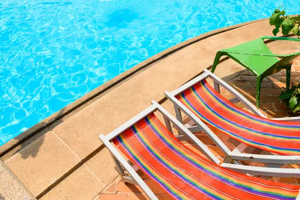 Yazlık tatil beldelerinde plaj ve deniz konsepti için yüzme havuzu manzaralı renkli plaj şezlongu ya da güneşli şezlong..