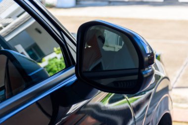 Modern siyah araba yan aynası 2024 'ün yan görüntüsü, açık hava bulanık arka plan.