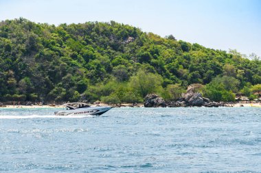 Pattaya, Tayland - 7 Mart 2024: Mavi deniz ve mavi açık gökyüzü arka planındaki Koh Larn adasında tropik plaj ve ada sabah manzarası. Sürat teknesi, feribot, tatil, yaz, tatil.