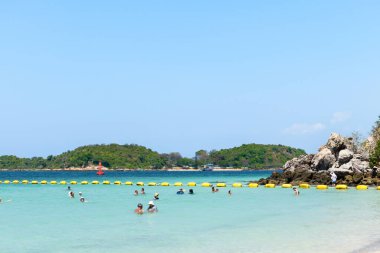 Pattaya, Tayland - 7 Mart 2024: Koh Larn adasındaki tropik bir sahil ve mavi denizin manzarası. Turist ya da Gezgin grubu ya da sahildeki birçok kişi. Tatil, Yaz, Tatil, Doğa, Rahatlama.