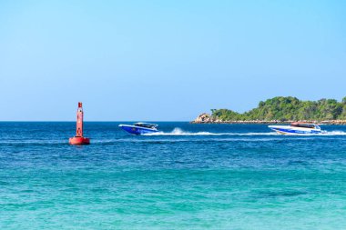 Pattaya, Tayland - 7 Mart 2024: Koh Larn adasında maviler içinde yüzen sürat teknesi. Sahilde bir grup turist ya da gezgin. Tatil, Yaz, Tatil, Sürat teknesi, Gemi, Etkinlik.