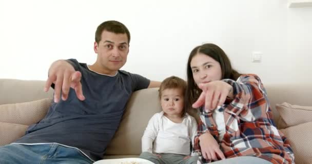 赤ちゃんのいる両親は家にいます 家族でソファで映画を見る — ストック動画