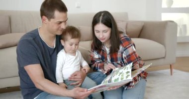 Aile, ebeveynlik ve insanlar kavramı - mutlu anne, baba ve bebek daugter okuma kitap evde.