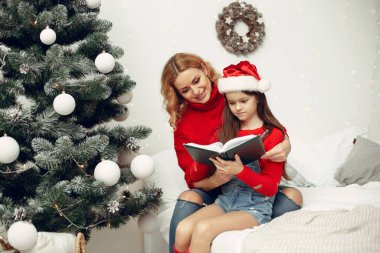 İnsanlar Noel için hazırlanıyor. Anne kızıyla oynuyor. Aile şenlik odasında dinleniyor. Kırmızı kazaklı çocuk..