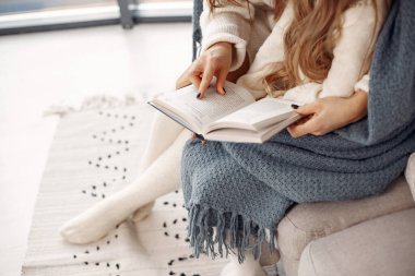 İnsanlar Noel için hazırlanıyor. Anne kızıyla oynuyor. Noel Baba şapkalı bir aile. Beyaz elbiseli küçük kız.