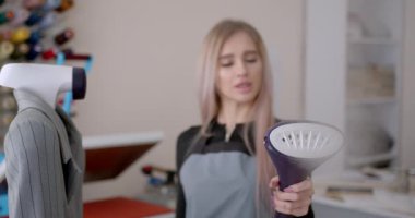 Giysi atölyesinde buhar ütüsü kullanan bir kadın. Kıyafet tasarlamak..