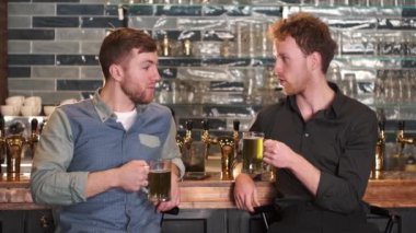 Two old friends are having conversation in pub over beer.