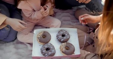 Beyaz, neşeli bir aile kadını ve ergen ve küçük kızları olan donut yiyen bir adam. Çocuklu aileler.