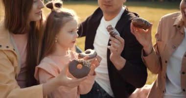 Beyaz, neşeli bir aile kadını ve ergen ve küçük kızları olan donut yiyen bir adam. Çocuklu aileler.