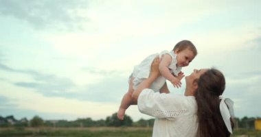 Doğada bebeğinin tadını çıkaran bir kadın. Yeşil yaz tarlasında kızını tutan bir anne..