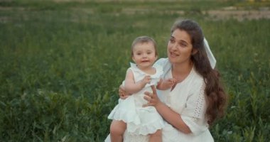 Doğada bebeğinin tadını çıkaran bir kadın. Yeşil yaz tarlasında kızını tutan bir anne..
