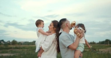 Mutlu, genç bir aile doğada, tatilde ve dışarıda birlikte vakit geçiriyor. Anne, babam kızını çimlerin üzerinde tutuyor. Aile tatili kavramı.