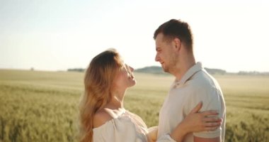 Bir adam hamile bir kadına sarılıyor. Yaz buğday tarlasında bir yürüyüş. Doğada piknik, tatil kavramı.