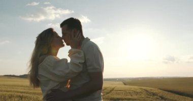 Bir adam hamile bir kadına sarılıyor. Yaz buğday tarlasında bir yürüyüş. Doğada piknik, tatil kavramı.