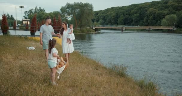 2人の子供を持つ幸せな家族は湖によって夏に屋外で楽しみを持っています 自然の中でリラックスしたスタイリッシュな家族 — ストック動画