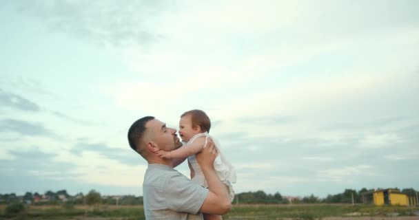快乐的家庭 父亲抱着女儿在田野中央 面对着蓝色的夏日天空 — 图库视频影像