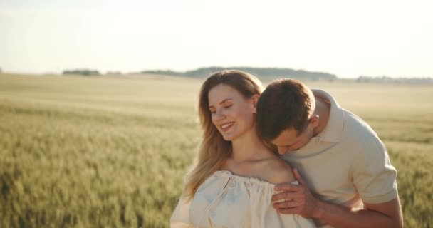 男は妊婦を抱きつく 夏の小麦畑を散歩 自然の中でピクニック 休暇のコンセプト — ストック動画