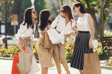 Kadın alışverişi. Şehirde dört zarif kadın var. Kadınlar alışveriş torbalarıyla yürür..