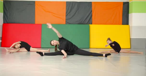 小女孩体操运动员和舞蹈家在一间五颜六色的房间里和一位女教练一起做伸展运动 业余爱好 生活方式 — 图库视频影像