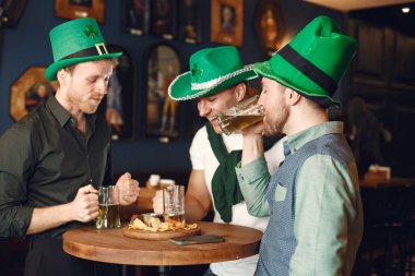 Men in green hats. Friends celebrate St. Patricks Day. Celebration in a pub.