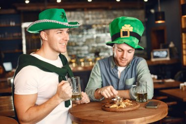 Men in green hats. Friends celebrate St. Patricks Day. Celebration in a pub.