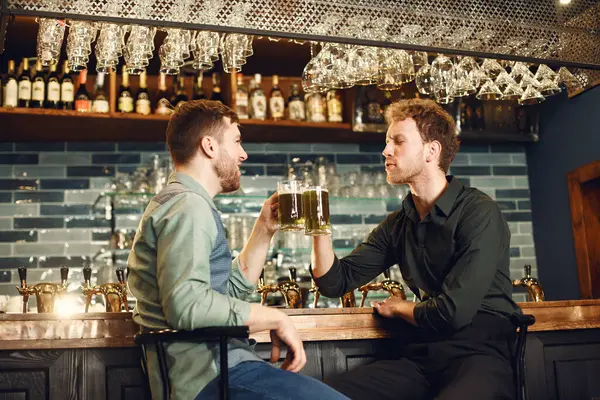 Men at bar. Guys drinking beer. Men communicate over a mug of beer.
