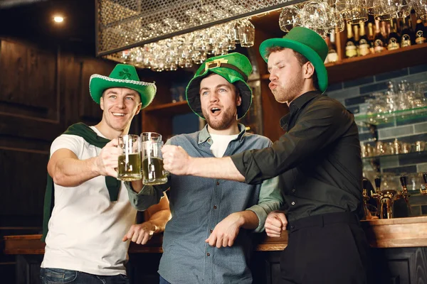 Men in green hats. Friends celebrate St. Patricks Day. Celebration in a pub.