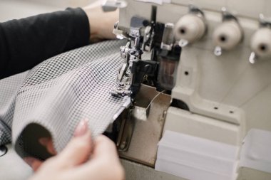 Dikiş atarken bir kadının ellerine odaklan. Genç bayan terzi dikiş makinesinin üzerinde terzilik stüdyosunda oturuyor. Atölyede dikiş diken kadın.