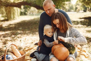 Sonbahar parkında bir aile. Ailesi olan sevimli küçük bir çocuk. Balkabaklı aile.