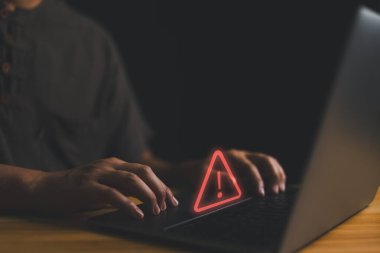 Kullanıcı, uyarı hatası ve bakım konsepti için üçgen uyarı işareti olan bilgisayar kullanıyor. Hacker saldırıları ve hackleme verileri, siber suçlar, fidye yazılımı, sahte yazılımlar, siber güvenlik.