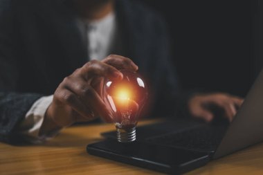 Yaratıcı bir fikir. Fikir ve yenilik kavramı, elinde ampul tutan iş adamı. Yaratıcı düşünme ve öğrenme. İnovasyon ve iş veya eğitim için ilham içeren bir fikir