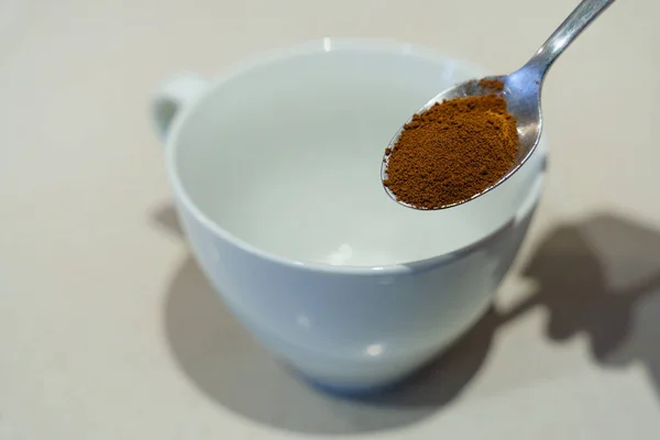 Morning Brew Magic: A Spoonful of Soluble Coffee. morning ritual with a small spoon delicately cradling soluble coffee  ready for a brew. In the background, a white mug stands prepared