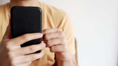 Sıradan Akıllı Telefon Kaydırma - Modern Dijital Boş Zaman. Sarı tişörtlü bir insan akıllı telefon ekranında kayarak vakit geçirir.