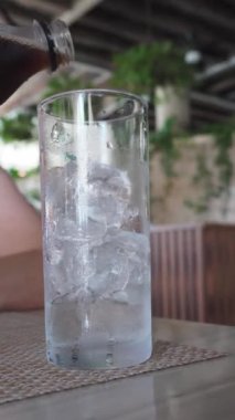 Eller buzla dolu bir bardağa siyah bir soda doldurur.