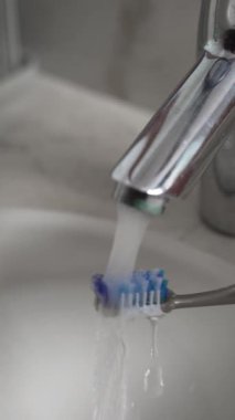 Diş fırçasını Akan Suyun Altında Duruluyorum. Banyo musluğundan akan su diş fırçasına akıyor.