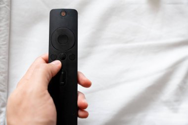 Elleri Siyah TV Uzaktan Kumandalı Beyaz Yatak Çarşafları Üzerinde Boşluk Kopyala