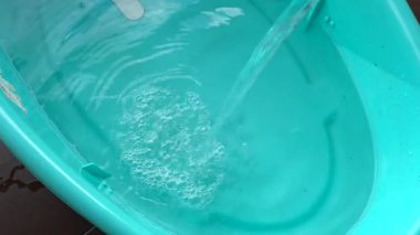 Mavi bir bebek küvetini su sıçratma ve baloncuklarla dolduran su akıntısının genel görünümü bebek bakımı, banyo zamanı, hijyen ve ev hayatıyla ilgili konular için mükemmel.