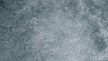 Su kabarcıkları hareket halinde, su yüzeyinde soyut bir desen ve doku oluşturuyor.