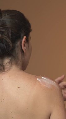 Açık tenli, çilli, omzuna ve sırtına beyaz krem sürmüş bir kadın. Negatif arkaplan, cilt rutinini, güneş korumasını ya da su kaybını gösteren