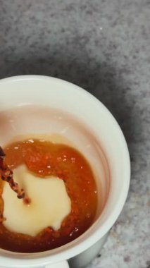 Sıcak kahvenin beyaz bir fincana dökülüşünün yavaş çekim görüntüsü.