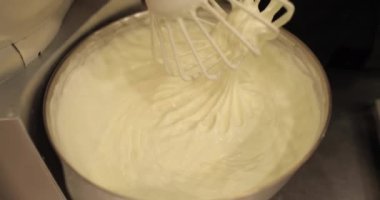 Kremanın tutarlılığını kontrol eden bir şekerlemecinin elinde büyük bir çırpıcı. Krema hazırlanıyor. Kremalı, çırpmalı, aşçı eli olan bir kâseye yaklaş..
