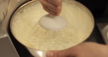 Kremanın tutarlılığını kontrol eden bir şekerlemecinin elinde büyük bir çırpıcı. Krema hazırlanıyor. Kremalı, çırpmalı, aşçı eli olan bir kâseye yaklaş..