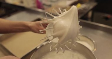 Kremanın tutarlılığını kontrol eden bir şekerlemecinin elinde büyük bir çırpıcı. Krema hazırlanıyor. Kremalı, çırpmalı, aşçı eli olan bir kâseye yaklaş..