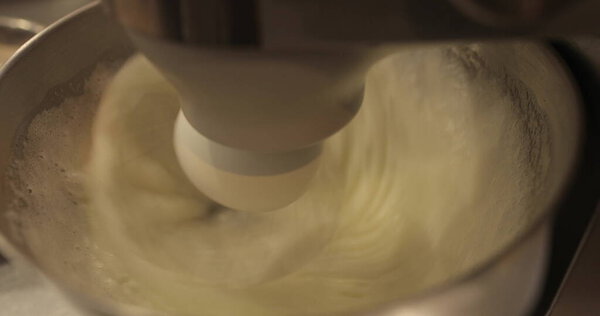 Whip the cream with an electric whisk. The work of a professional blender close-up. Whipped cream. The cream reaches hard peaks. Close up video shot