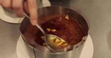 Profesyonel bir pastacının çikolatalı pastasını hazırlarken çikolatalı pastaya karamelize elma ekleme süreci. 4k 'da yakın çekim, UHD. Lezzetli yemek..