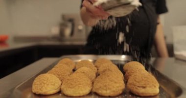 Bir kadın şekerci kurabiye pişirmek için metal bir yüzeye serpiştirilmiş şekerleme serpiştiriyor. Profesyonel bir şekerlemecinin işi..