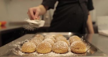 Bir kadın şekerci kurabiye pişirmek için metal bir yüzeye serpiştirilmiş şekerleme serpiştiriyor. Profesyonel bir şekerlemecinin işi..