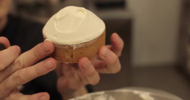 Kremalı tart hazırlamak için. Kremayı yaydığı sırada hamur işi şefinin elinde mini bir tart. Pasta şefi tartı beyaz kremayla süslüyor.